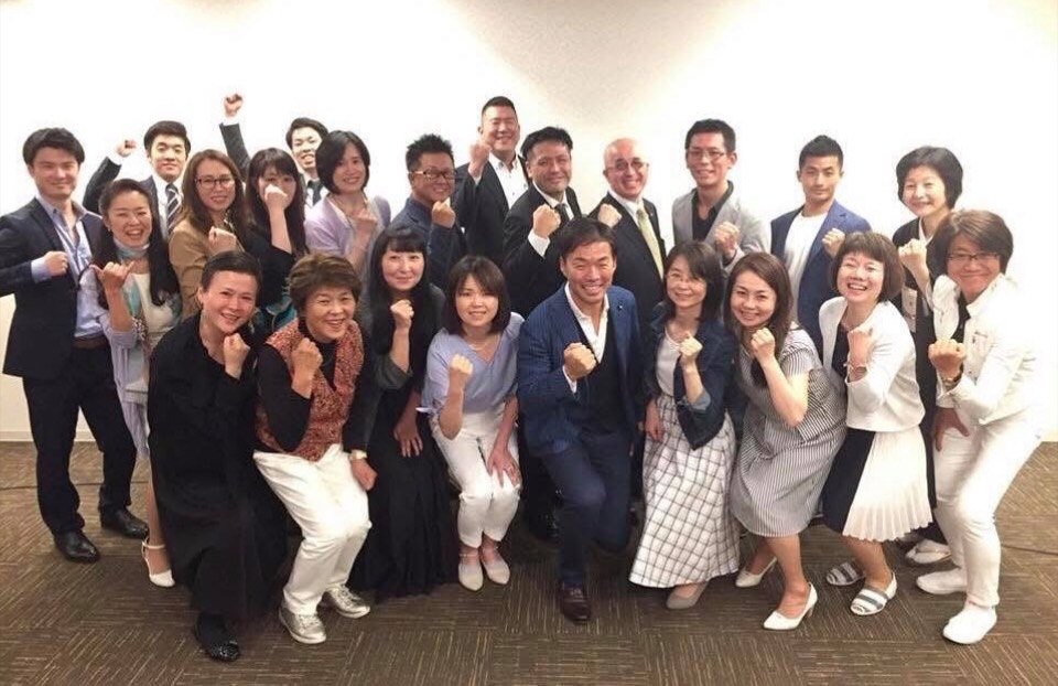 こぶしを掲げて笑う参加者たちと潮田英之